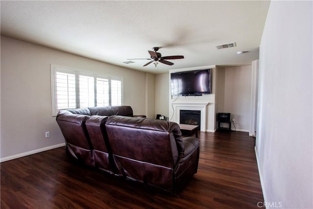 living area featuring wood finished floors, visible vents, a fireplace, ceiling fan, and baseboards