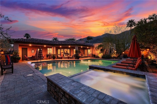 view of swimming pool featuring a mountain view, a patio area, and a pool with connected hot tub