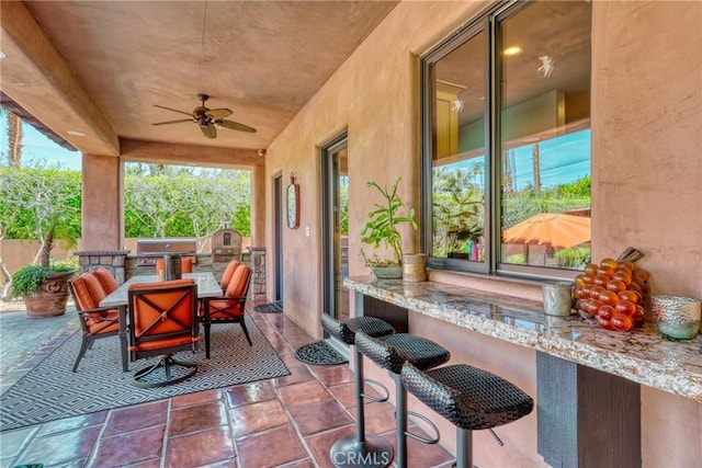 view of patio with an outdoor kitchen, outdoor dining area, and ceiling fan