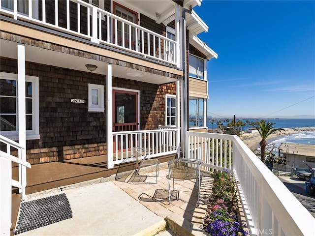 exterior space featuring a water view, covered porch, and a balcony