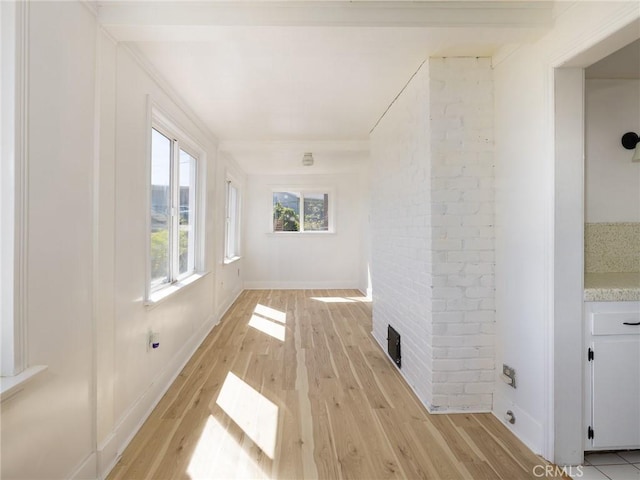 interior space with baseboards, brick wall, and light wood-style flooring