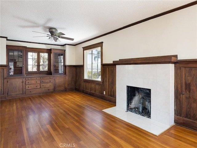 unfurnished living room featuring wood finished floors, a ceiling fan, a textured ceiling, and crown molding