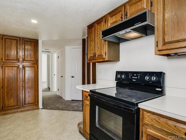 1714 Woodlark Ln, Fallbrook, CA 92028 - kitchen featuring black / electric stove, under cabinet range hood, brown cabinetry, light countertops, and a textured ceiling