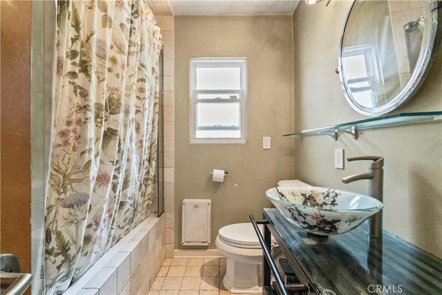 full bathroom with tile patterned flooring, toilet, tiled shower / bath combo, and a sink