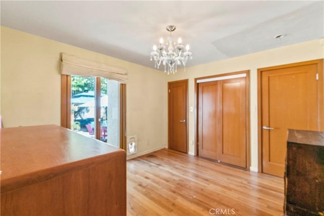 unfurnished bedroom with an inviting chandelier and light wood-style floors