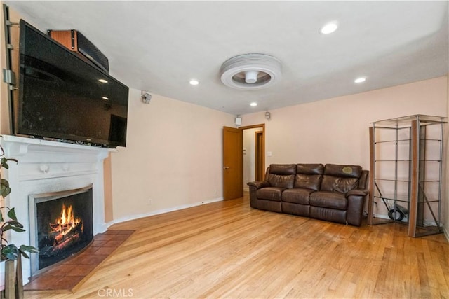 living area featuring a fireplace with flush hearth, wood finished floors, and recessed lighting