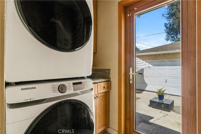 laundry area with cabinet space and stacked washer and clothes dryer