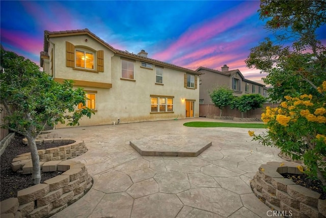 3184 Toopal Dr, Oceanside, CA 92058 - back of house at dusk featuring a fenced backyard, a patio, a chimney, and stucco siding