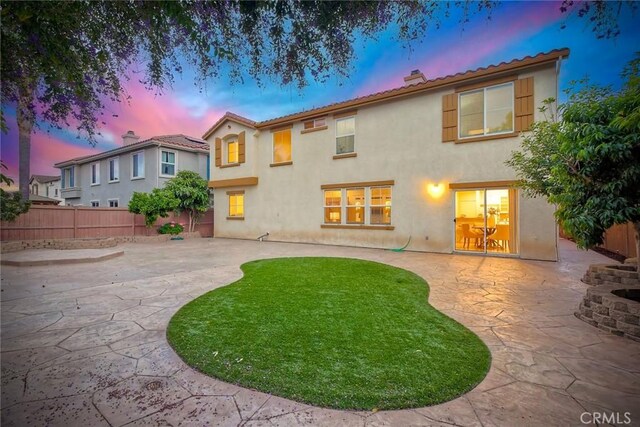3184 Toopal Dr, Oceanside, CA 92058 - back of house at dusk featuring a patio area, a fenced backyard, stucco siding, and a chimney