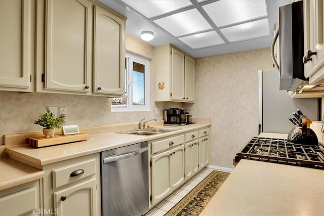 57716 Juarez Dr, Yucca Valley, CA 92284 - kitchen with appliances with stainless steel finishes, a sink, cream cabinets, light tile patterned floors, and wallpapered walls