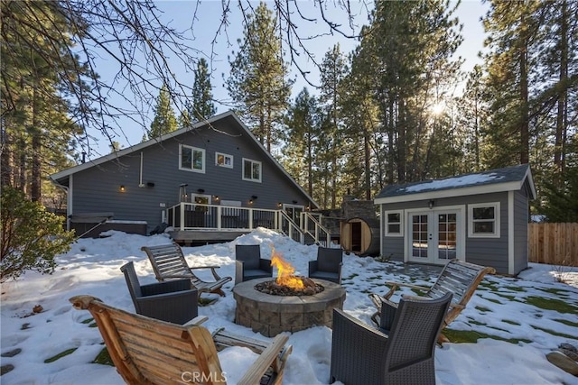 41496 Comstock Ln, Big Bear Lake, CA 92315 - snow covered back of property with fence, an outdoor fire pit, french doors, a deck, and an outdoor structure