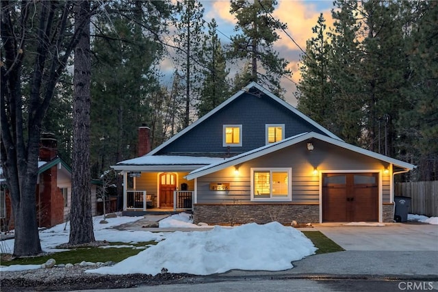 41496 Comstock Ln, Big Bear Lake, CA 92315 - rustic home featuring a porch, a chimney, a garage, stone siding, and driveway