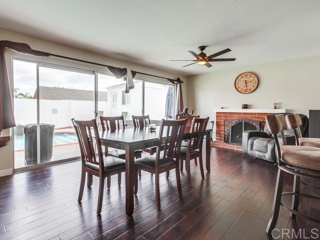dining space with a ceiling fan, dark wood-style floors, and a brick fireplace
