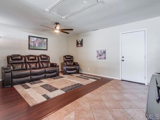 living room with baseboards, attic access, ceiling fan, and light tile patterned flooring