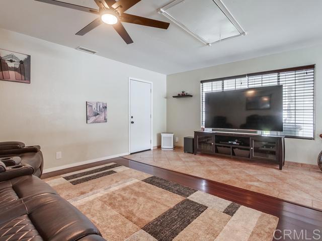 living area with a ceiling fan, attic access, visible vents, wood finished floors, and baseboards