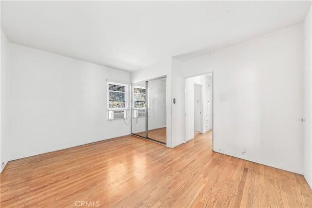 unfurnished bedroom with cooling unit, light wood-style flooring, and a closet