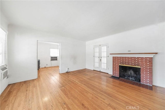 unfurnished living room featuring french doors, wood finished floors, and a fireplace