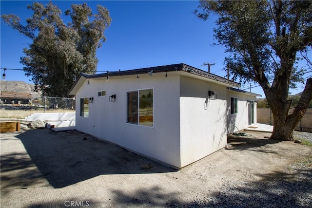 view of property exterior featuring stucco siding, a patio, and fence