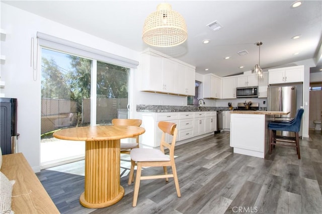 kitchen with visible vents, a sink, stainless steel appliances, white cabinets, and vaulted ceiling