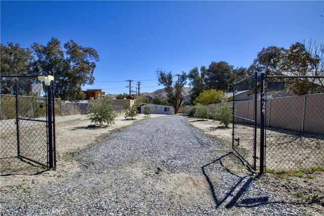 view of street with a gated entry, gravel driveway, and a gate