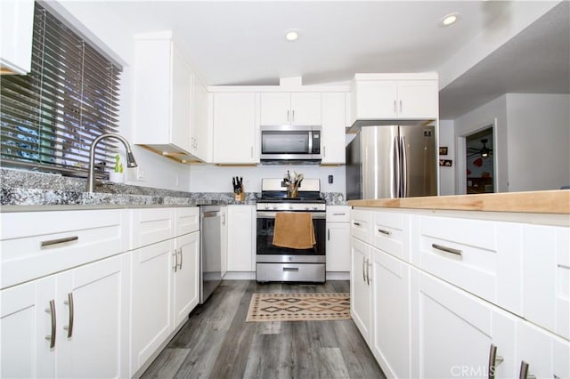 kitchen featuring dark wood finished floors, recessed lighting, white cabinetry, and appliances with stainless steel finishes