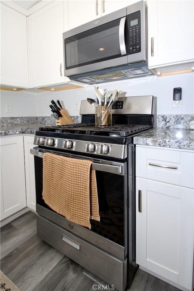 kitchen featuring white cabinets, wood finished floors, and appliances with stainless steel finishes