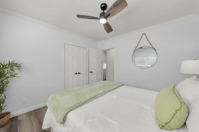 bedroom with baseboards, wood finished floors, a closet, ceiling fan, and ornamental molding
