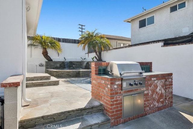 view of patio with an outdoor kitchen, area for grilling, and fence