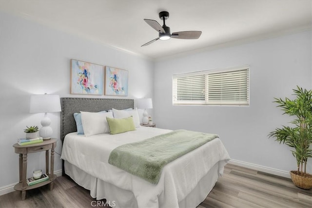 bedroom with baseboards, wood finished floors, ornamental molding, and ceiling fan