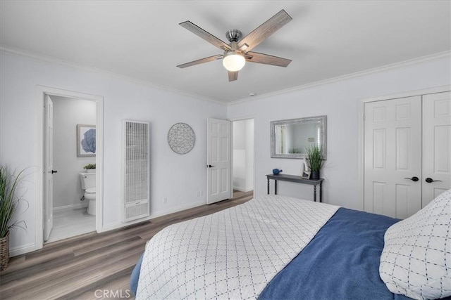 bedroom with wood finished floors, crown molding, baseboards, and a heating unit