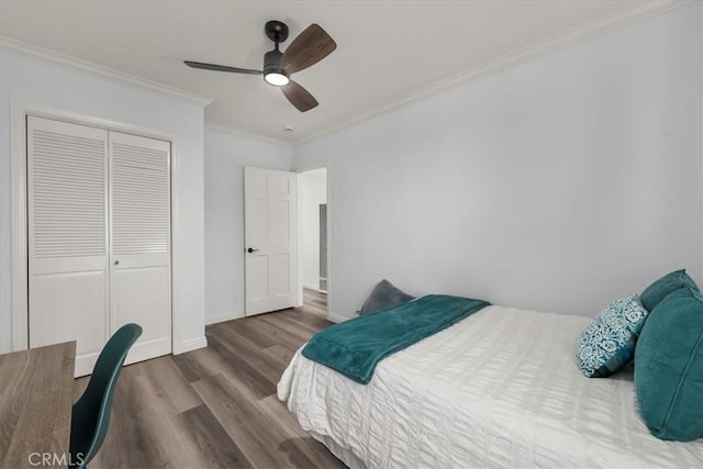 bedroom with wood finished floors, a closet, ceiling fan, baseboards, and ornamental molding
