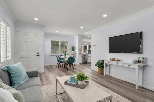 living area featuring recessed lighting, light wood-style floors, crown molding, and baseboards