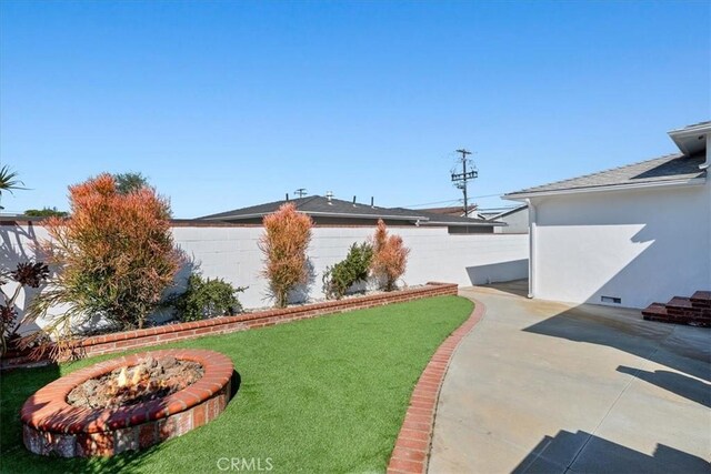 view of yard with fence, a fire pit, and a patio