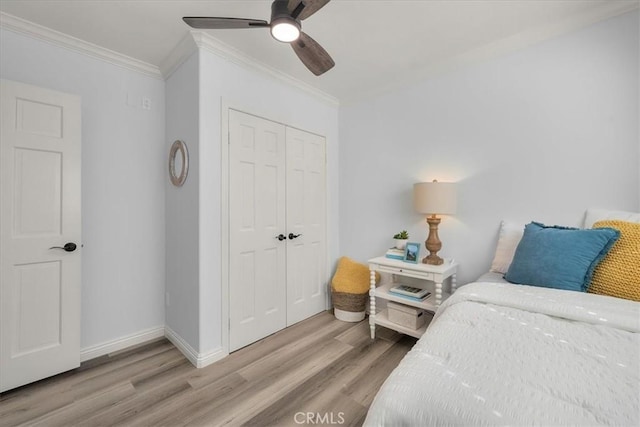 bedroom featuring crown molding, a closet, light wood-style floors, ceiling fan, and baseboards