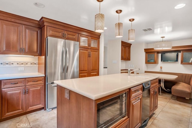 kitchen featuring visible vents, a sink, freestanding refrigerator, black microwave, and brown cabinetry