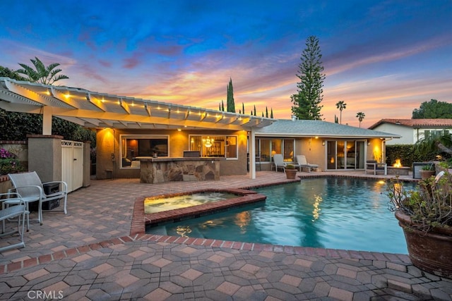 back of house featuring a pergola, a pool with connected hot tub, stucco siding, a patio, and outdoor dry bar