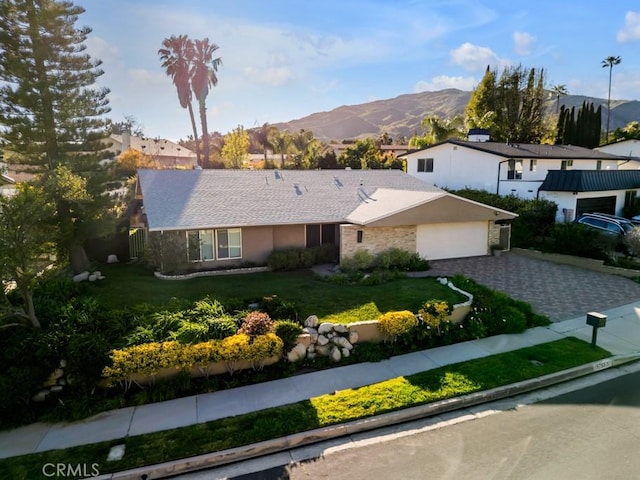 single story home with an attached garage, a mountain view, a front yard, and driveway