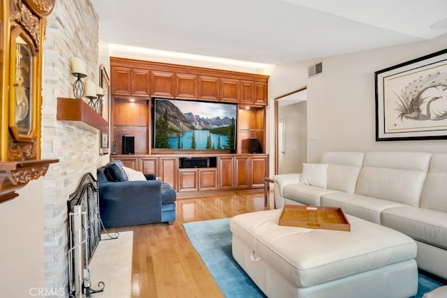 living room with light wood finished floors, a fireplace, and visible vents
