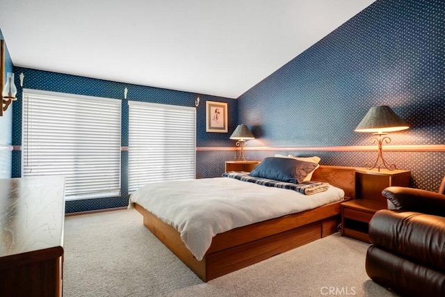 carpeted bedroom with wallpapered walls, multiple windows, and vaulted ceiling