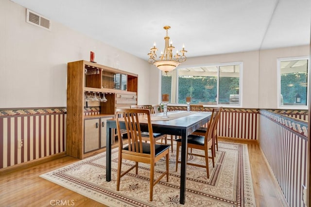 dining space with light wood-type flooring, a notable chandelier, and visible vents