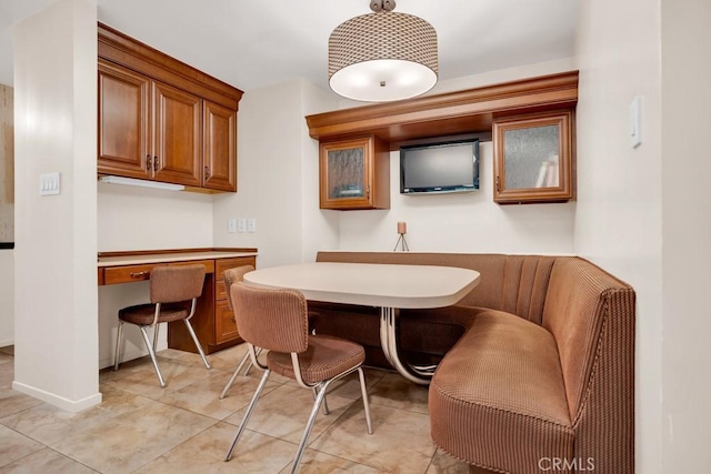 dining room featuring built in study area, light tile patterned floors, and baseboards