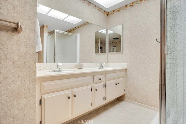 bathroom with a sink, a skylight, double vanity, and a stall shower