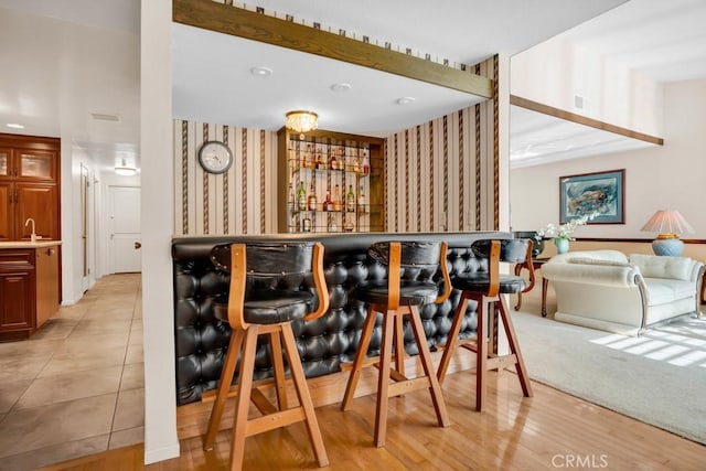 bar with wallpapered walls, bar area, a sink, and visible vents