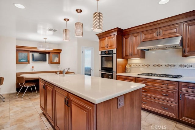kitchen featuring under cabinet range hood, visible vents, a center island with sink, stainless steel appliances, and a sink