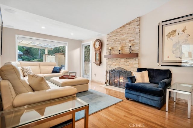 living area with baseboards, a stone fireplace, recessed lighting, wood finished floors, and lofted ceiling