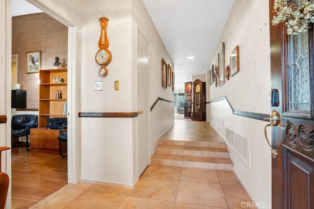 hall featuring visible vents, baseboards, and light tile patterned flooring