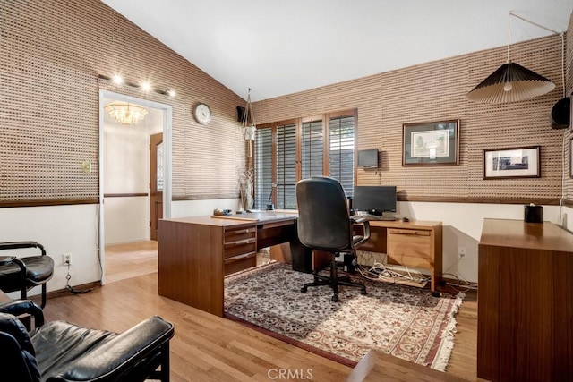 office area featuring wood finished floors, baseboards, lofted ceiling, and a notable chandelier
