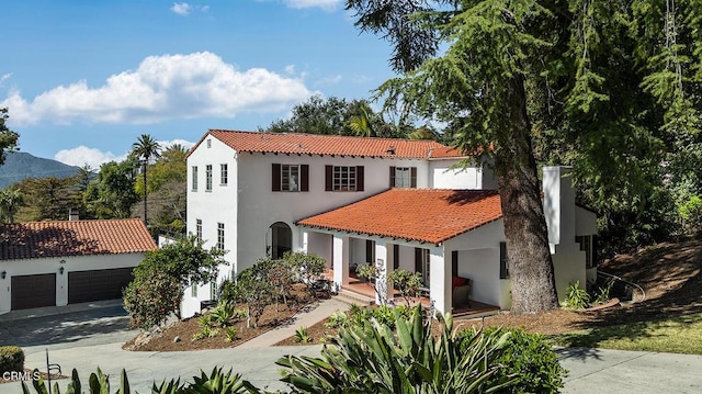 mediterranean / spanish-style home featuring aphalt driveway, stucco siding, an attached garage, and a tile roof