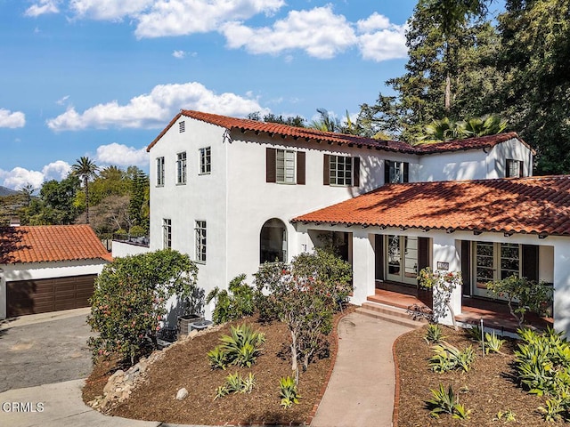 mediterranean / spanish-style house featuring a tile roof, concrete driveway, stucco siding, french doors, and a garage