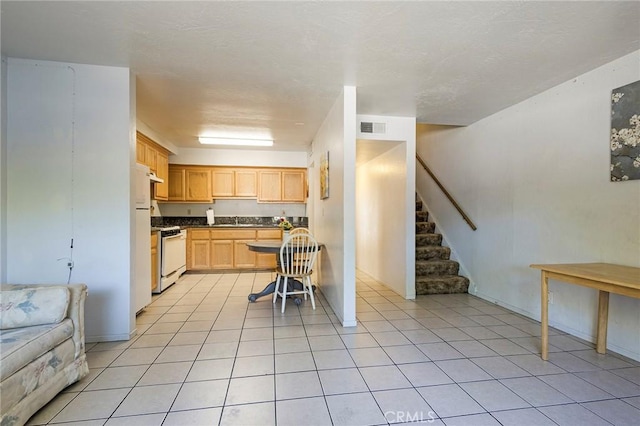 609 Rancheria Dr, Chico, CA 95926 - kitchen with light brown cabinets, range, light tile patterned flooring, freestanding refrigerator, and dark countertops